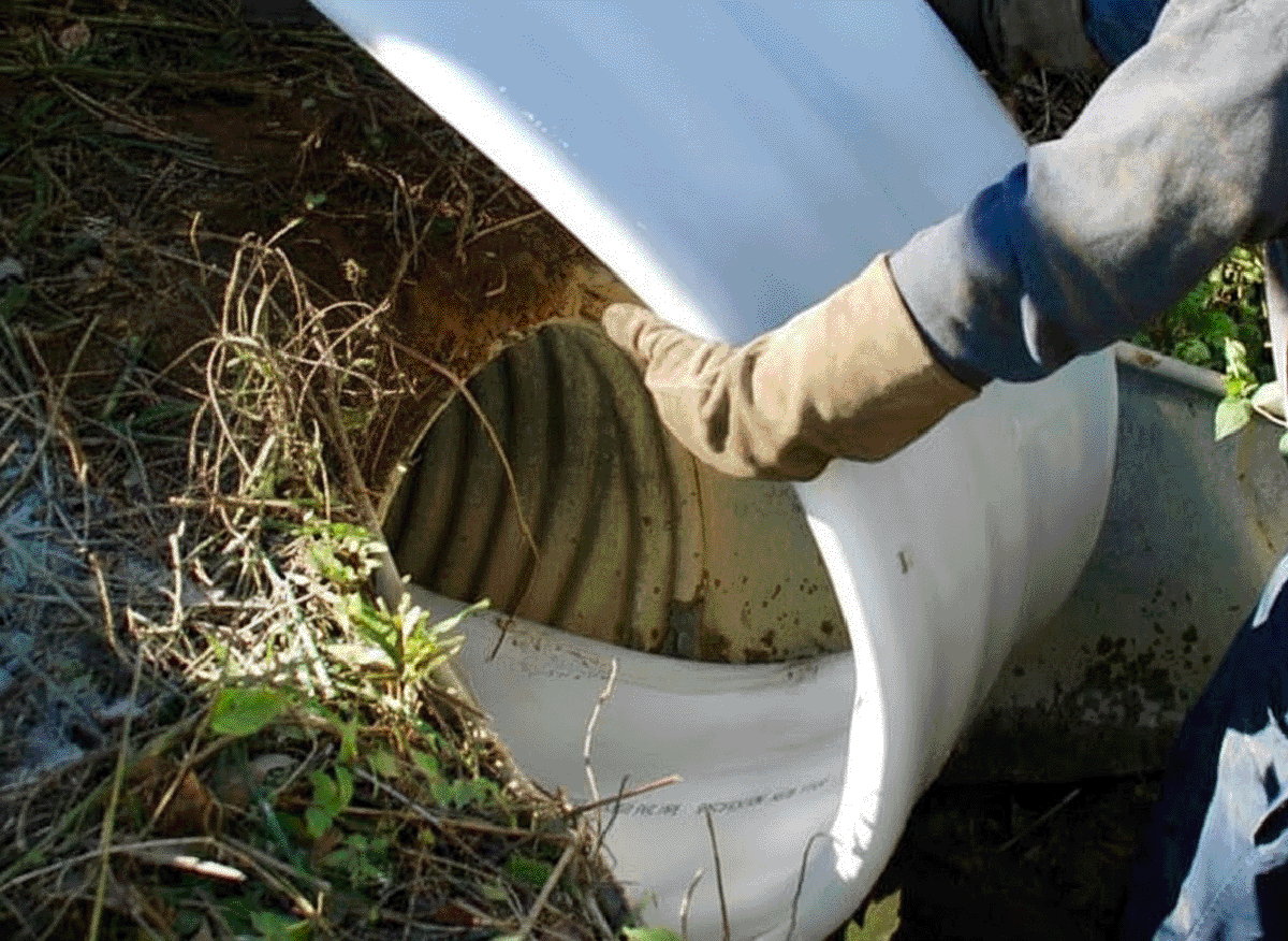 Technician inserting a PVC liner into a large, old drain pipe